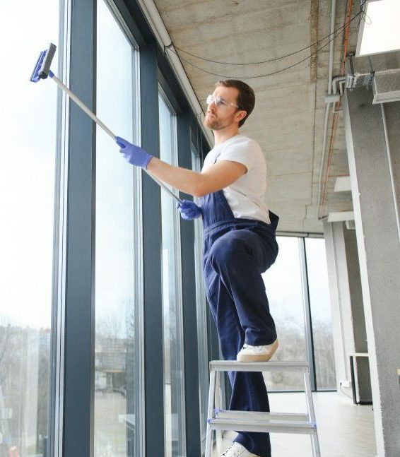 Professional window cleaner in blue overalls using a squeegee on floor-to-ceiling windows in an Austin office building — eco-friendly, same-day service