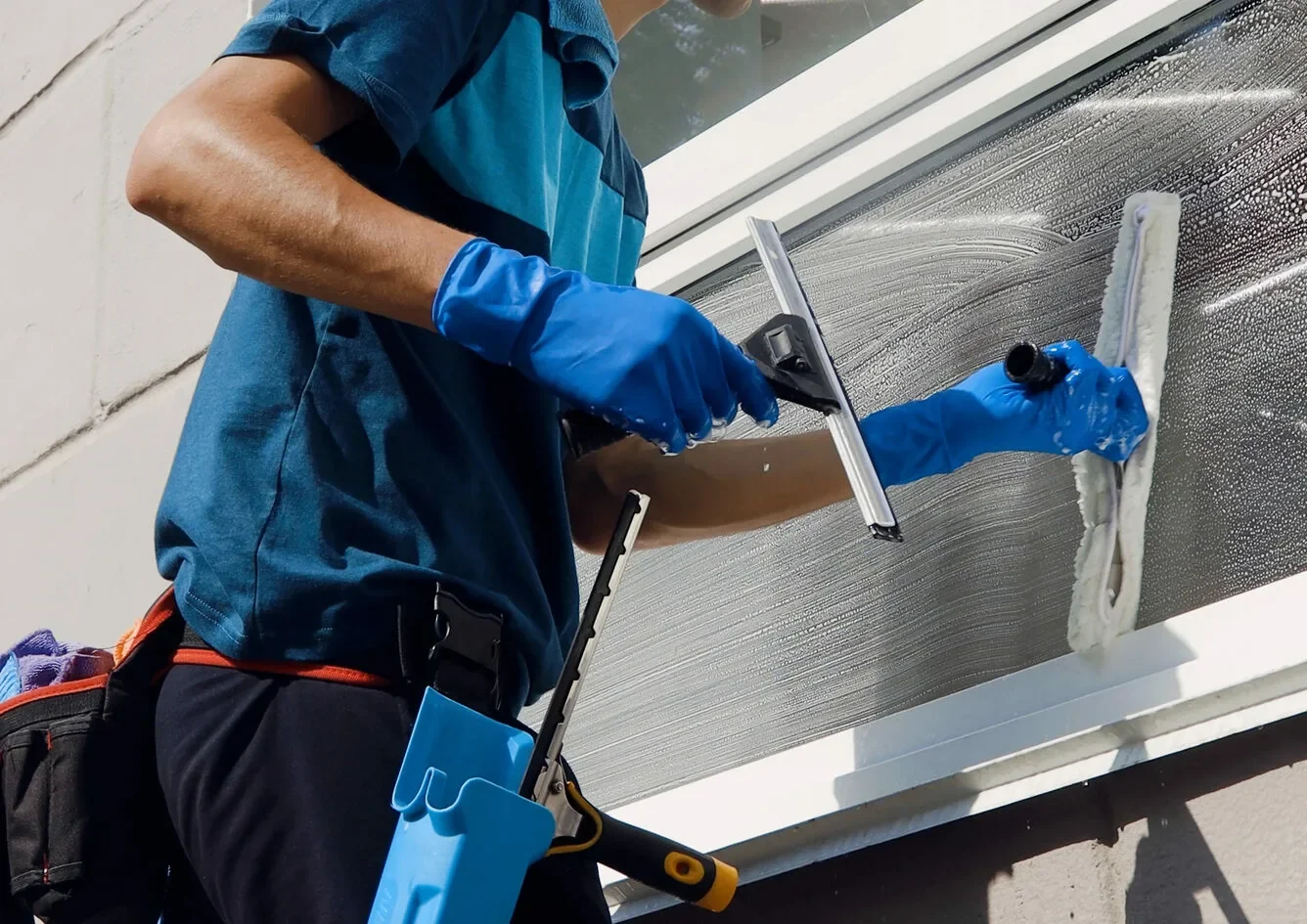 Close-up of a Gleaming Space cleaner using dual-action squeegee and scrubber on residential window frame in Austin — pet-safe, streak-free finish