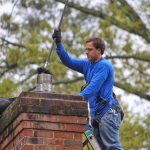 Professional chimney cleaning service by Gleaming Space, showing a technician removing creosote and soot buildup from a residential chimney to prevent fires and improve drafting in CO, TX, and WA.