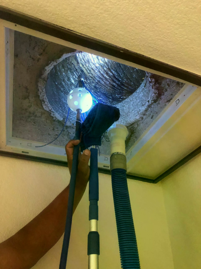 HVAC specialist in protective mask cleaning and sanitizing commercial or residential ventilation system, ensuring thorough contaminant removal and air quality improvement