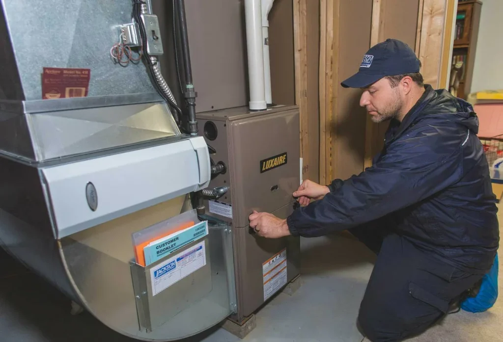 HVAC technician performing furnace cleaning and maintenance service on heating system