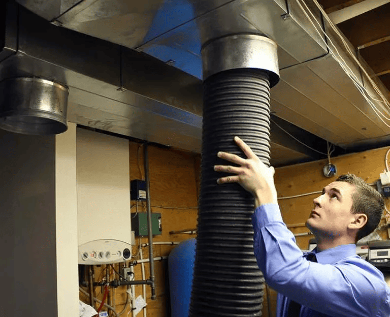 Licensed duct cleaning technician operating professional air duct cleaning equipment with flexible extraction hose for comprehensive commercial ductwork cleaning service