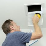 A Gleaming Space technician uses a rotary brush tool to clean a ceiling-mounted supply vent grille during residential air duct cleaning—removing dust, allergens, and pet dander to improve indoor air quality in CO, TX, or WA homes.