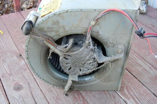 Extremely dirty blower motor with heavy dust and debris accumulation on blower wheel and housing, showing critical need for professional blower motor cleaning and HVAC maintenance service